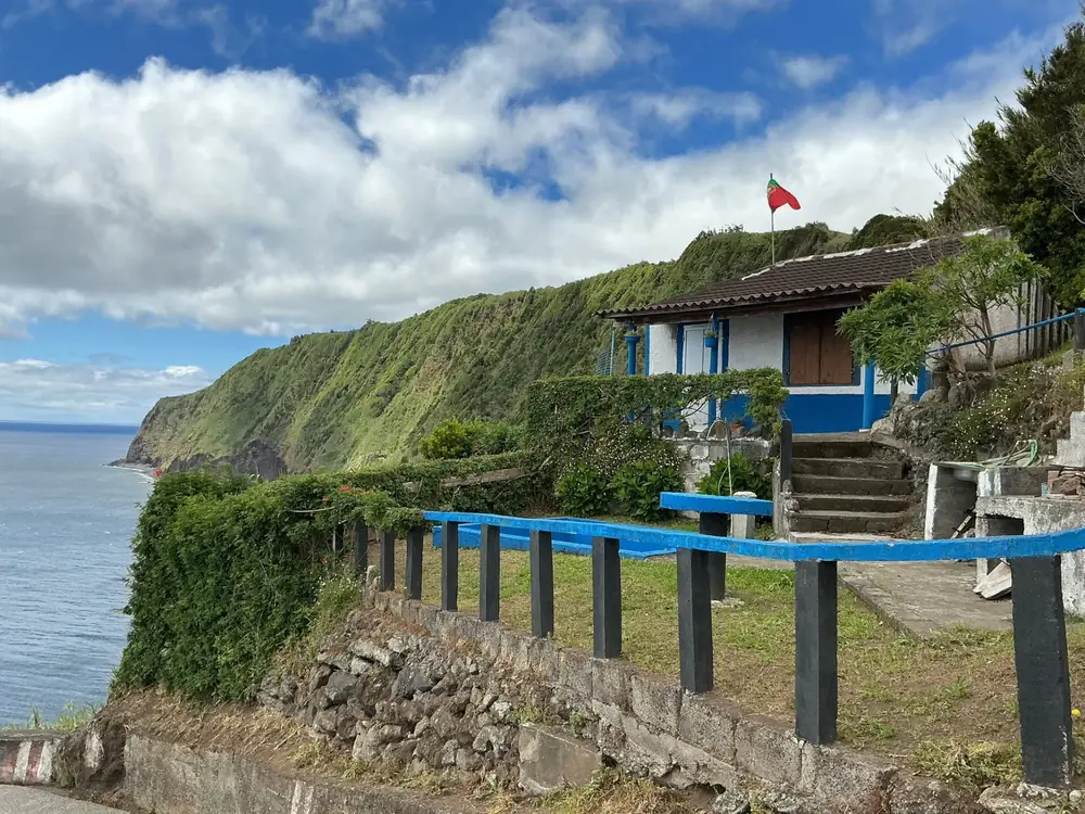 Petite maison bleue et blanche accrochée à la falaise